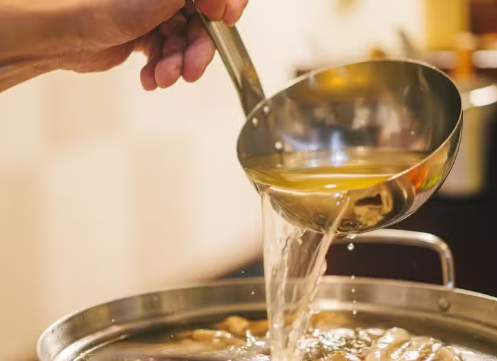 Dashi broth being ladled over oden